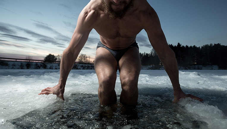 Mand sænker sig ned i isvand 